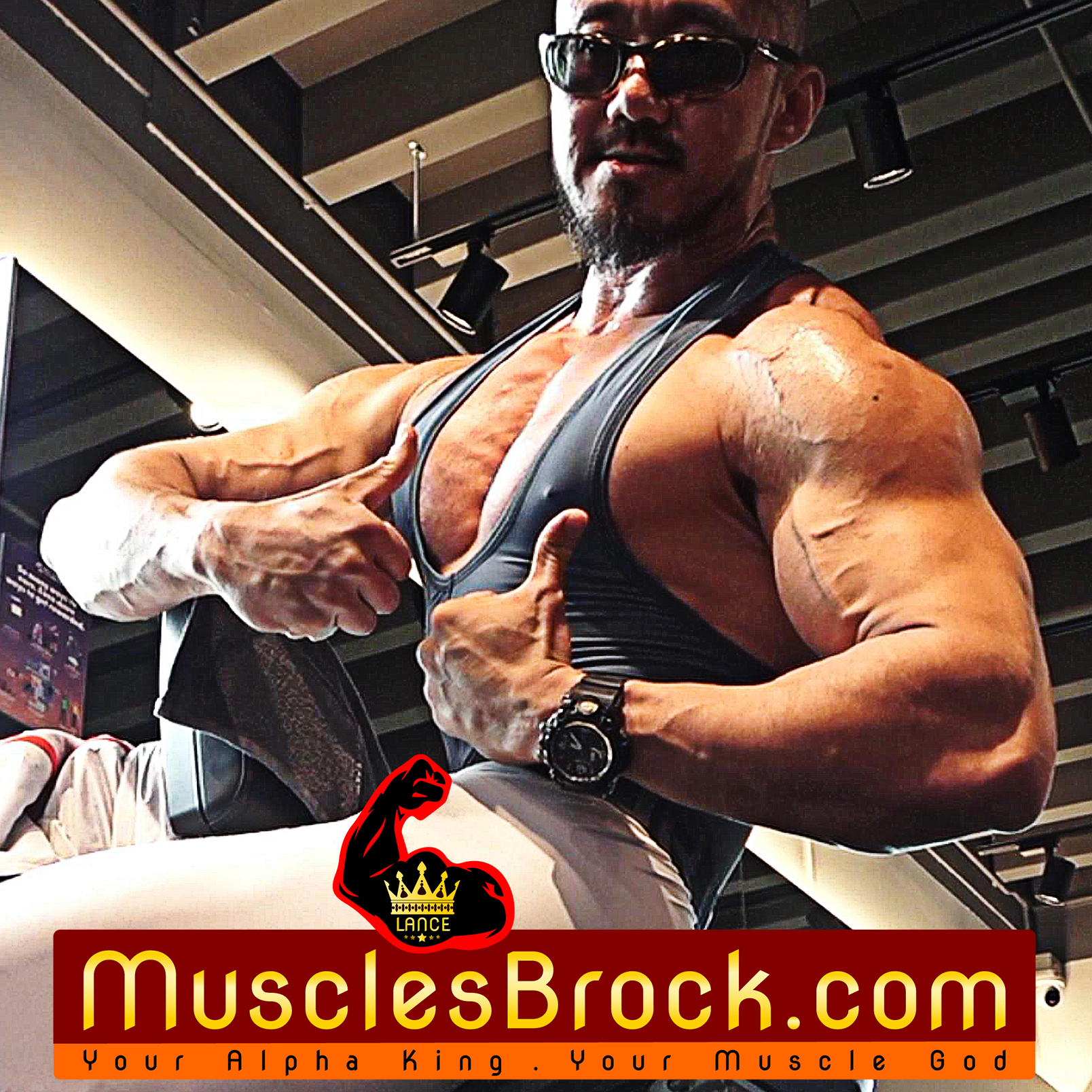 Muscular bodybuilder flexing chest and arms in gym, wearing slate grey compression singlet and sunglasses, MusclesBrock.com banner with crown logo — Titan Era alpha physique branding.